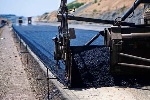 Paver hopper discharging fresh asphalt onto a prepared roadbed