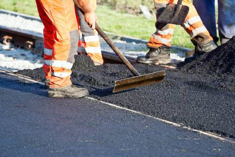 Paving crew raking fresh asphalt into place