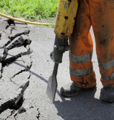 Worker at site working with pneumatic plugger hammer - Turnkey Asphalt