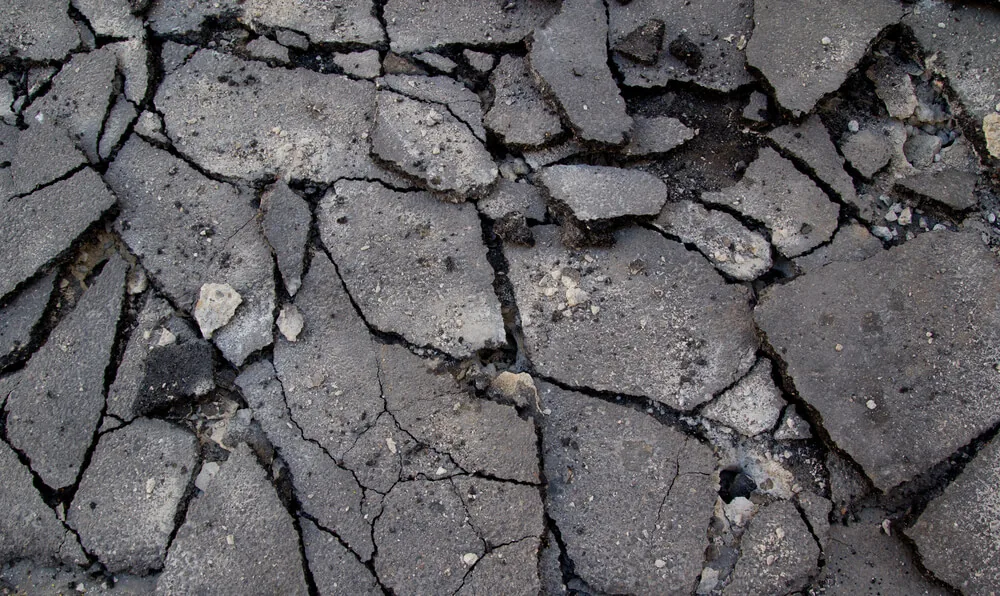 Asphalt surface broken into many cracked pieces