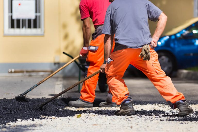 Crew spreading and levelling hot asphalt across a prepared area