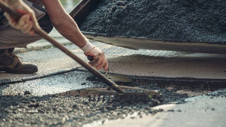 Fresh asphalt being raked level into a cut-out repair