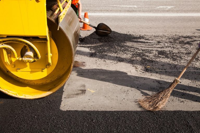 A roller compacting a fresh asphalt surface while it is still hot