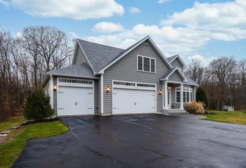 A gray-walled suburban house with white asphalt driveway