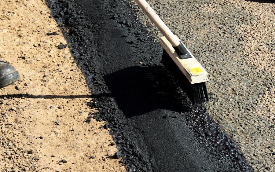Fresh asphalt spread along a repaired edge