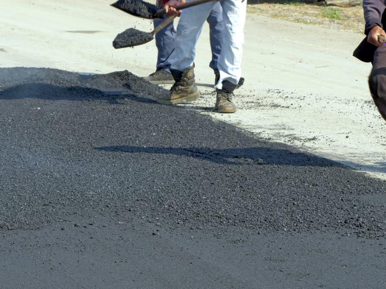 Hot mix shovelled into a repair before it is compacted